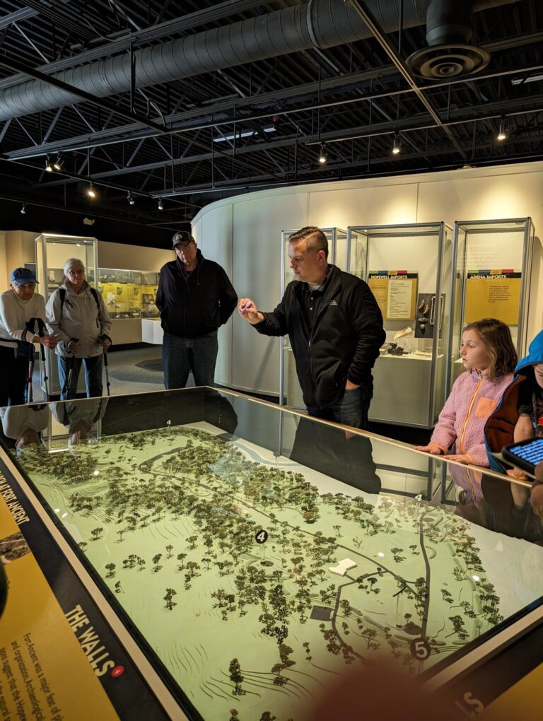 Site manager of Fort Ancient, Bill Kennedy, gives a tour to visitors in the museum. He pauses over a diorama, showcasing the scale of the site.